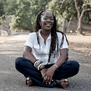 Dr. Lesley-Ann Noel smiling and sitting in front of trees.