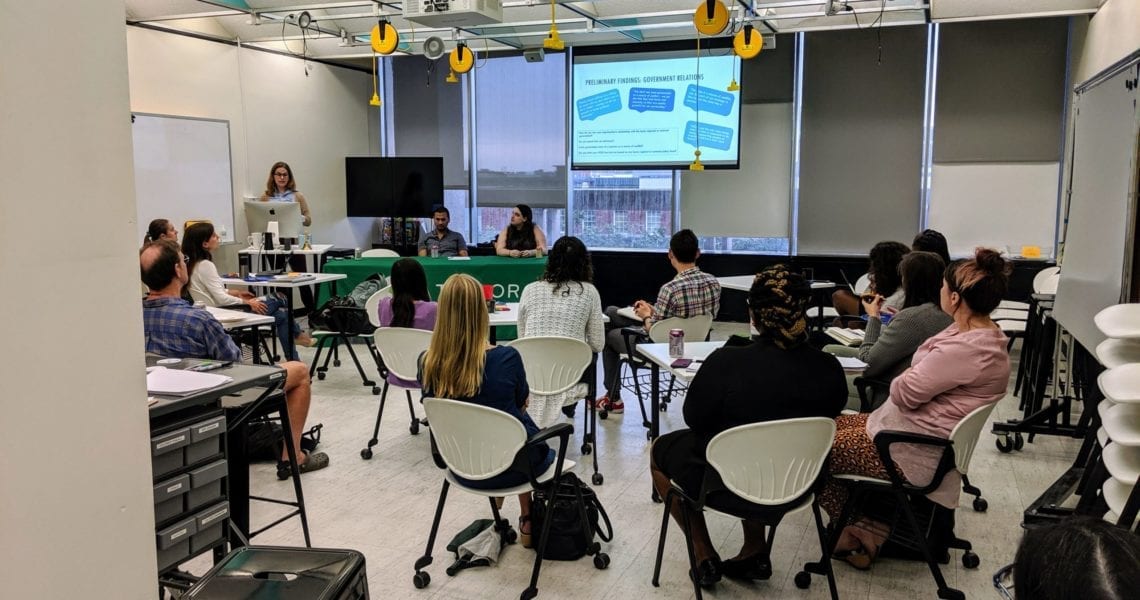Attendees Of The October 2019 Taylor Social Innovation Conversation Sit In The Taylor Classroom Listening To The Presenters Speak At A Table.