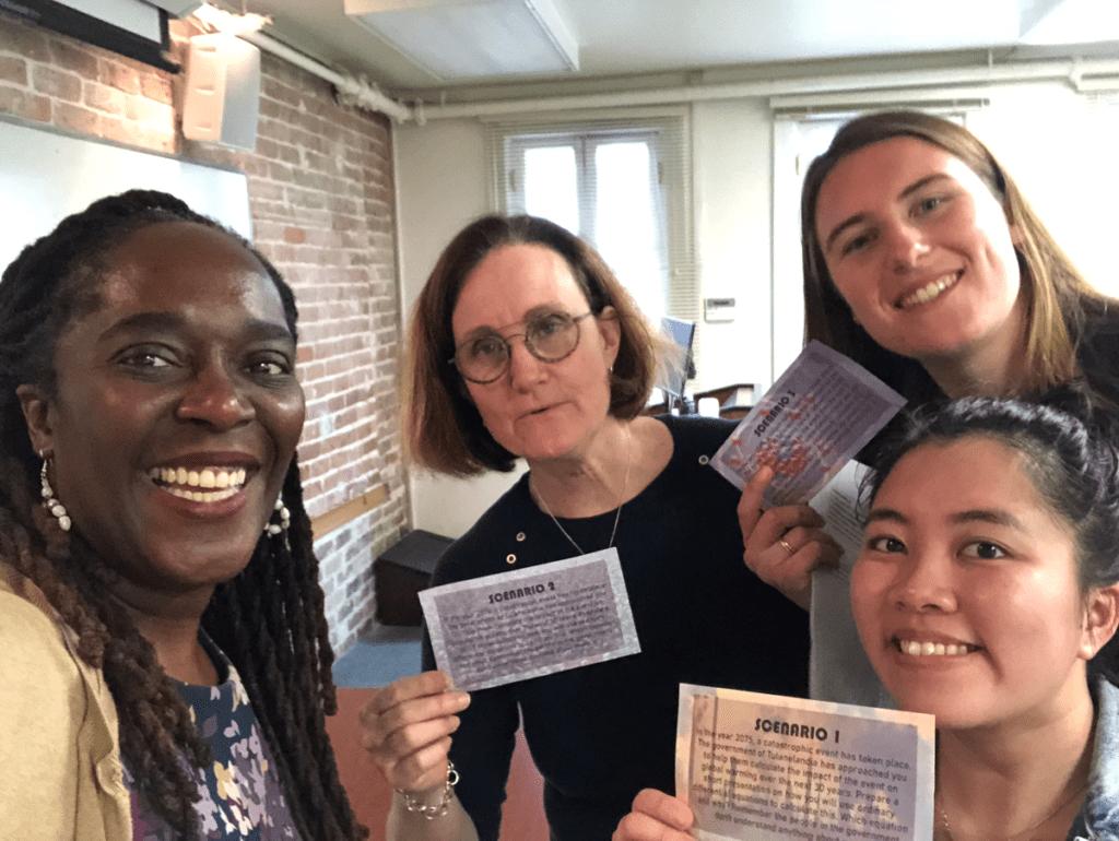 Four women smiling holding index cards.