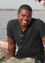 A person smiling for the camera wearing a black shirt in front of a river.