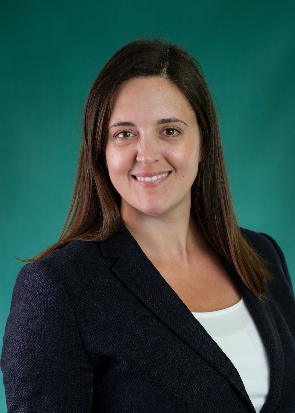 A professional headshot of Rebecca Otten, a smiling woman with straight, medium brown hair, wearing a navy blazer over a white top, posed against a solid teal background.